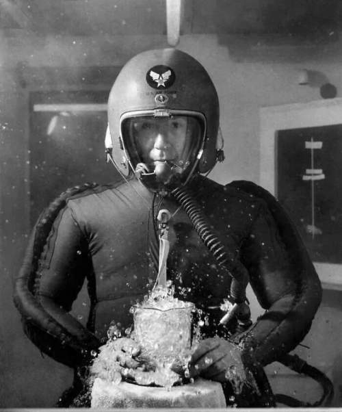 Человек в скафандре со стаканом кипящей воды в вакуумной камере, имитирующей высоту 65 000 футов, 8 февраля 1953 года.